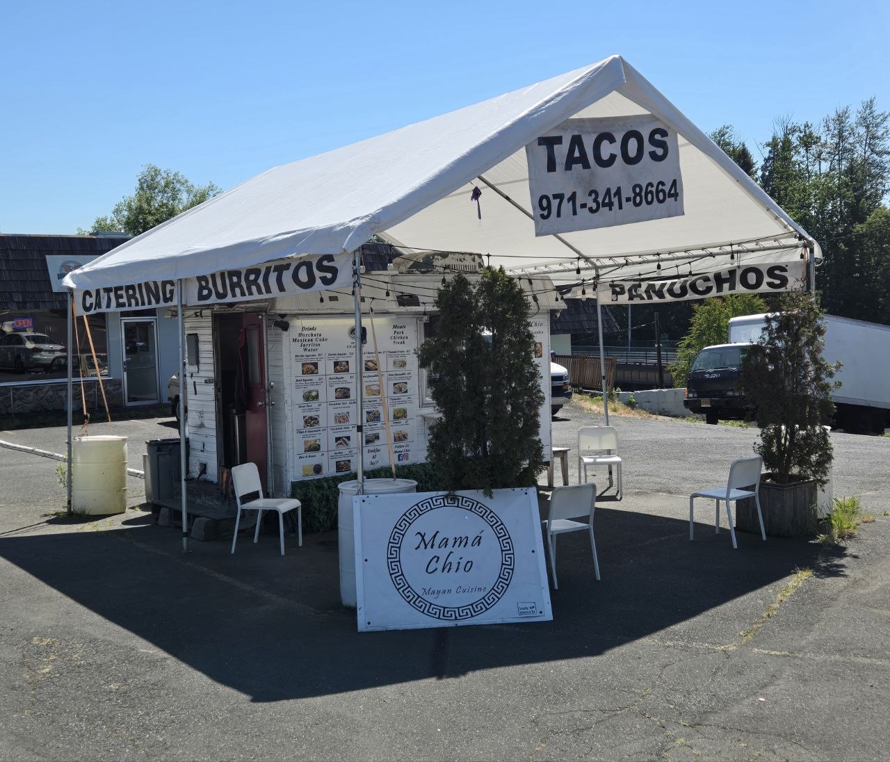 The Mexican food stand is set up under a white canopy tent on a sunny day.
