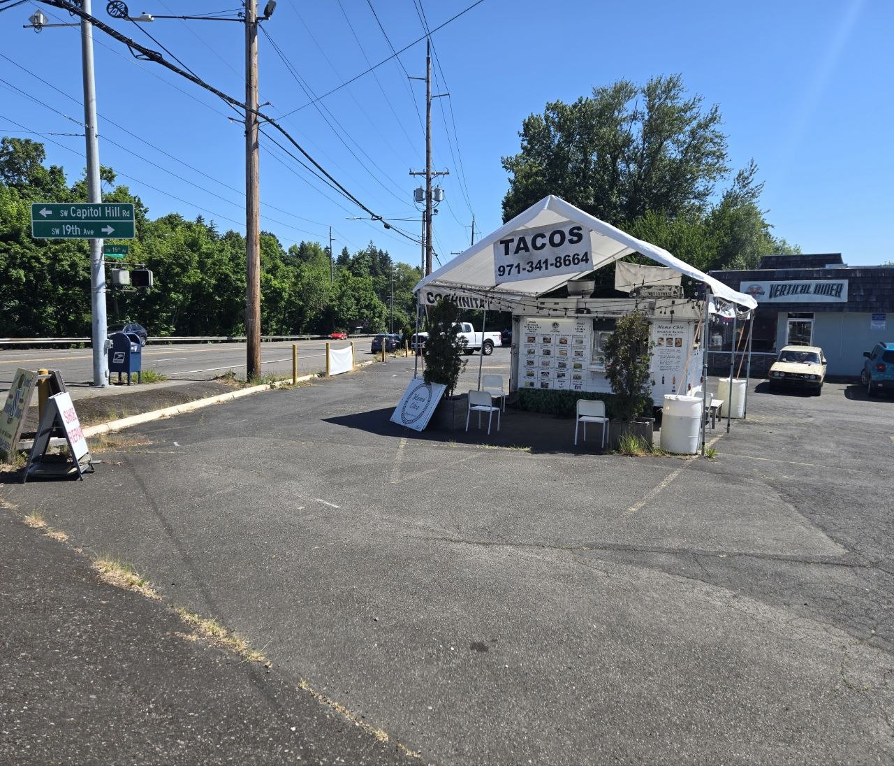 The taco stand is situated in a large, open asphalt parking lot.